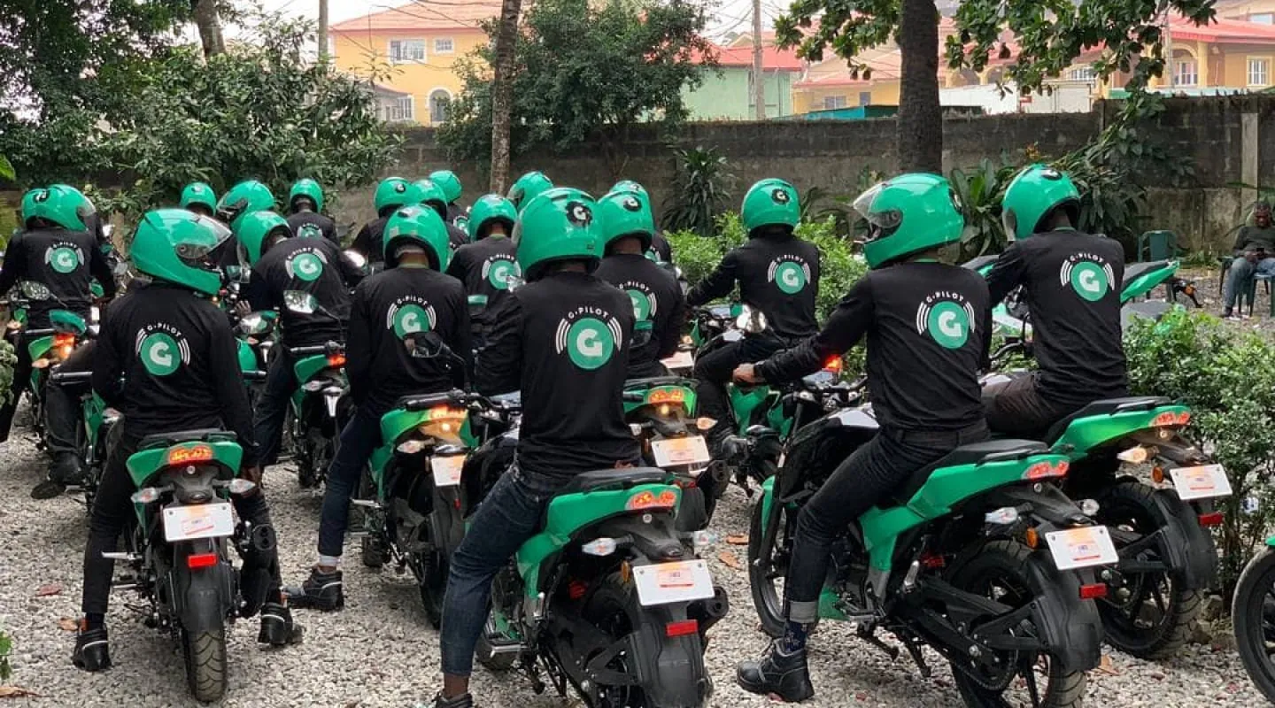 Group of motorcycle riders in green helmets and black uniforms gathered on green bikes in a residential area