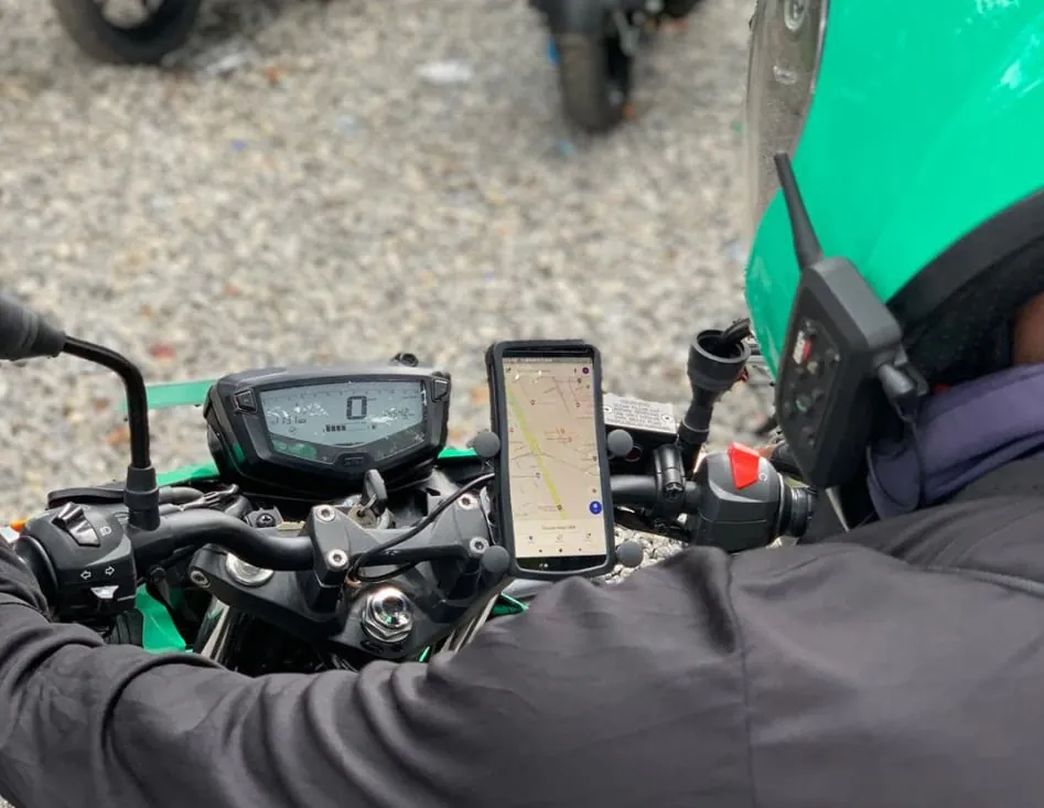First-person view on motorcycle dashboard with mounted smartphone on handlebar and navigation map on screen