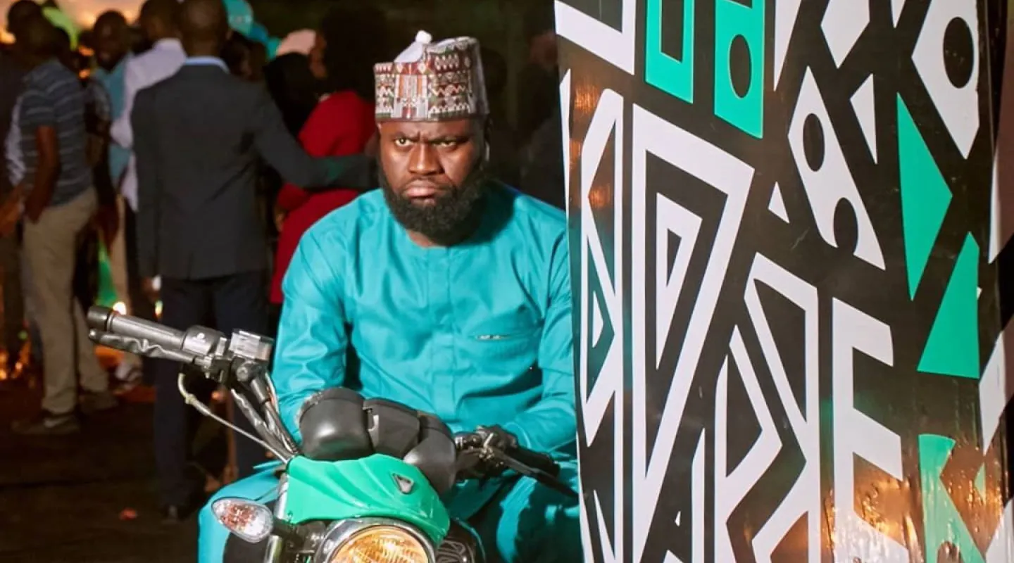 Sad man in traditional Nigerian attire on bike at event