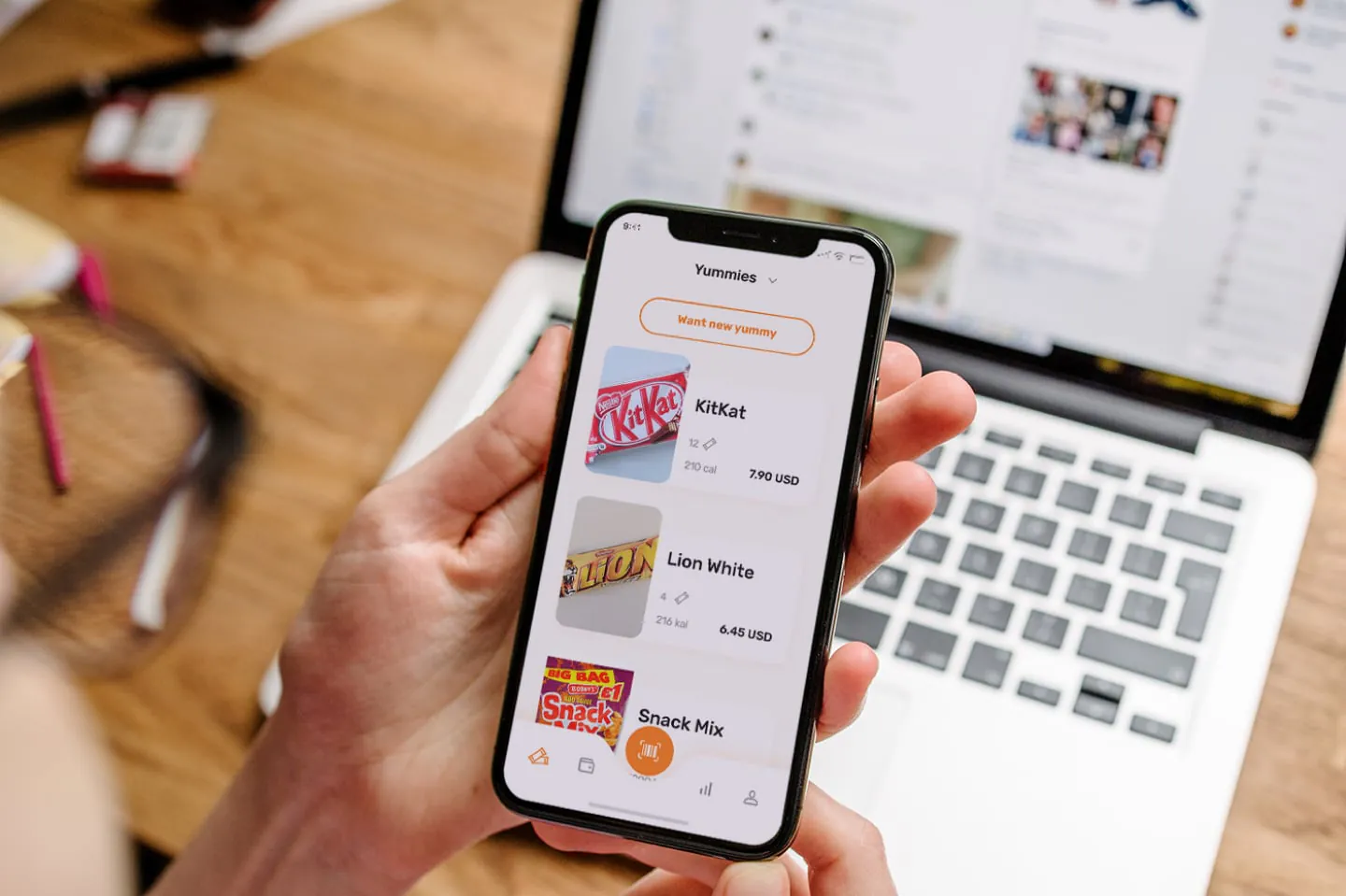 Hands holding a smartphone with a yummies list on an office snack service cross-platform app