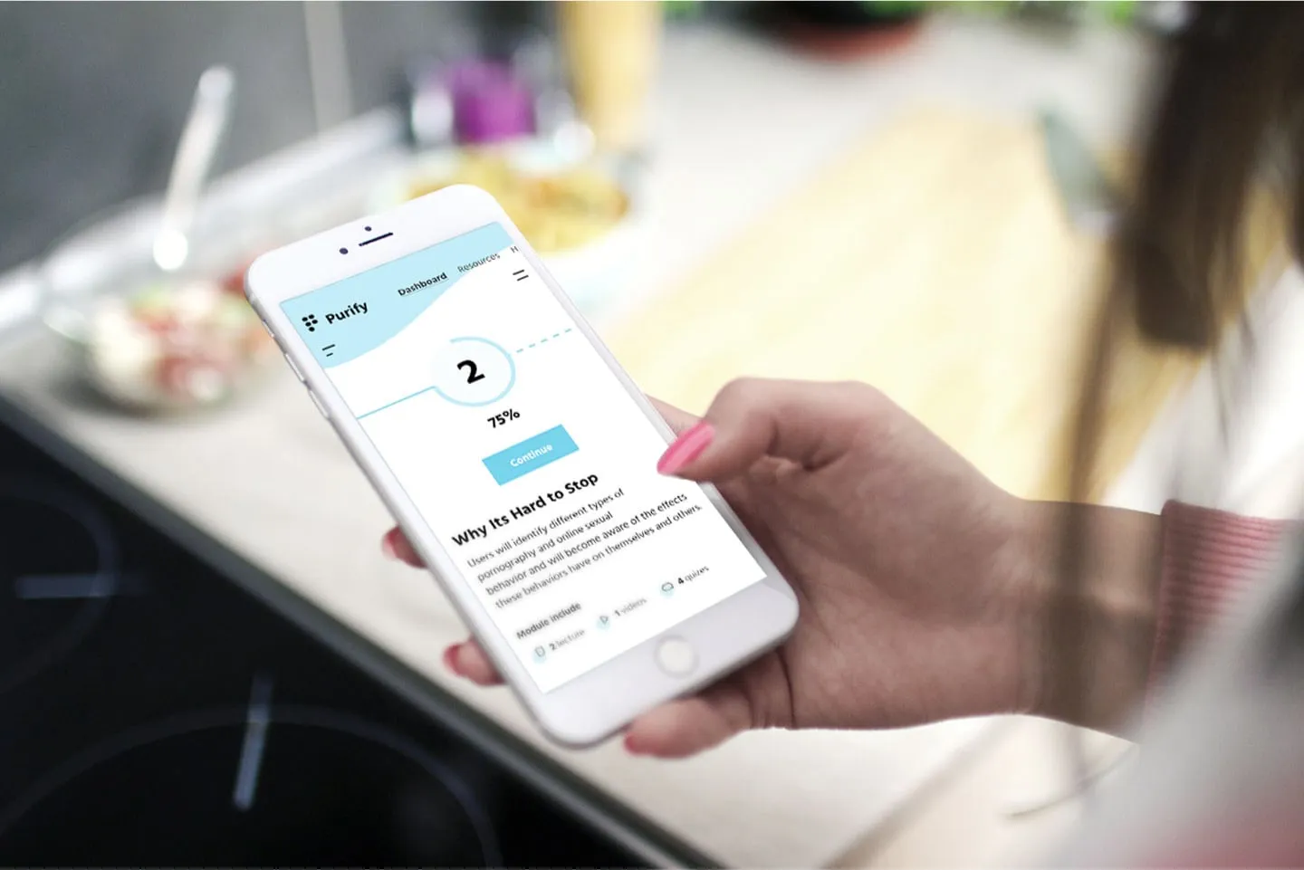 iPhone held over kitchen counter showing wellness app with information about awareness of porn dependency