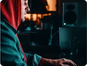 Man in red hoodie and jeans jacket working on pc